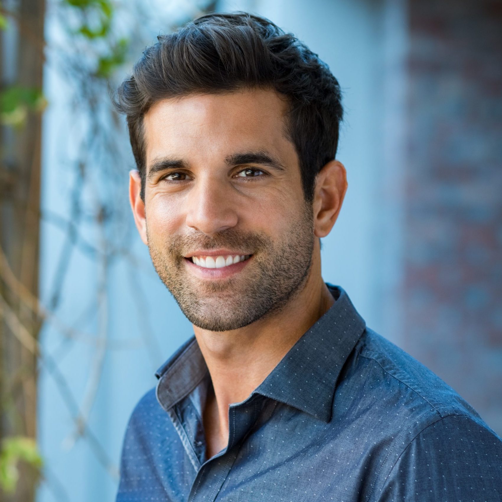 Handsome mid adult man smiling and looking at camera. Portrait of happy young casual man. Close up portrait of hispanic guy standing outdoor.