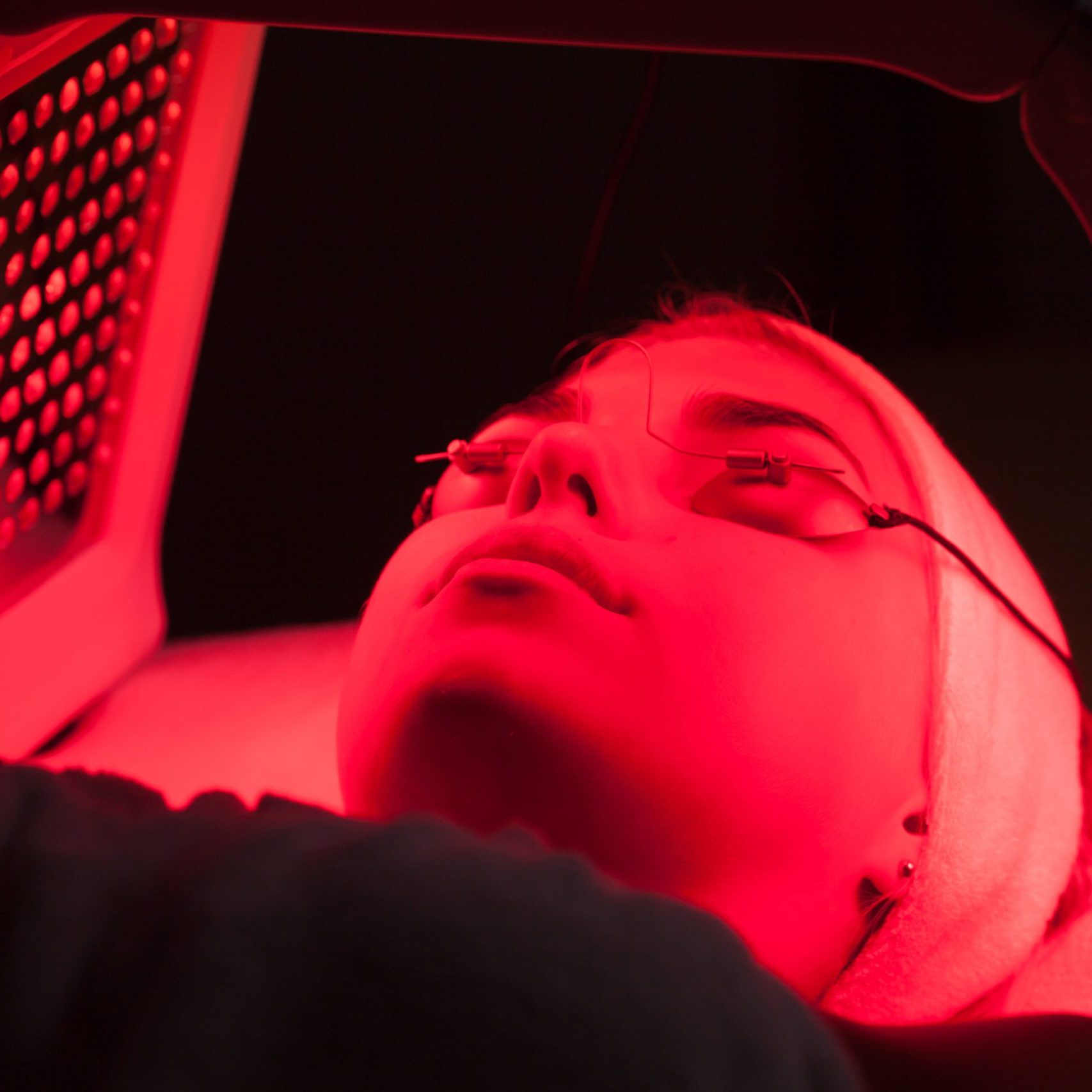 Young woman having LED light facial treatment in beauty salon